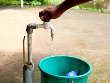 Eski bir plastik musluğu açan bir çocuğun eli.