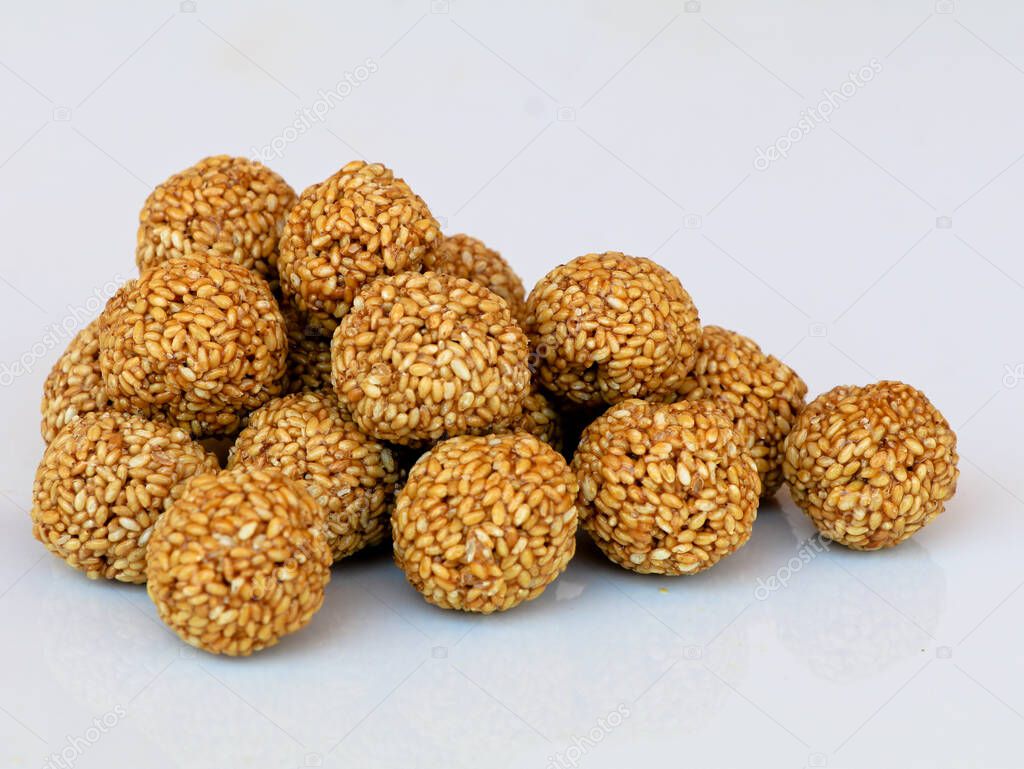 White sesame seed balls made with heated jiggery, tasty and nutritious candy , against white background