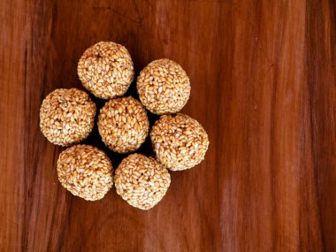 Tahta arka planda ısıtılmış jiggery, lezzetli ve besleyici şeker ile yapılan beyaz susam topları