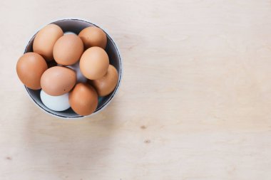 Yumurtalar ahşap zemine konur. Yemek malzemesi. Ahşap arka planda, kasedeki çiğ tavuk yumurtalarının yakın plan görüntüsü..