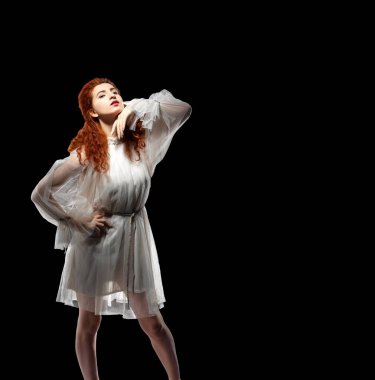 Siyah arka planda, beyaz tasarımcı elbisesi giymiş, ince, kızıl saçlı, kıvırcık saçlı bir kız. Şık gelinlik..