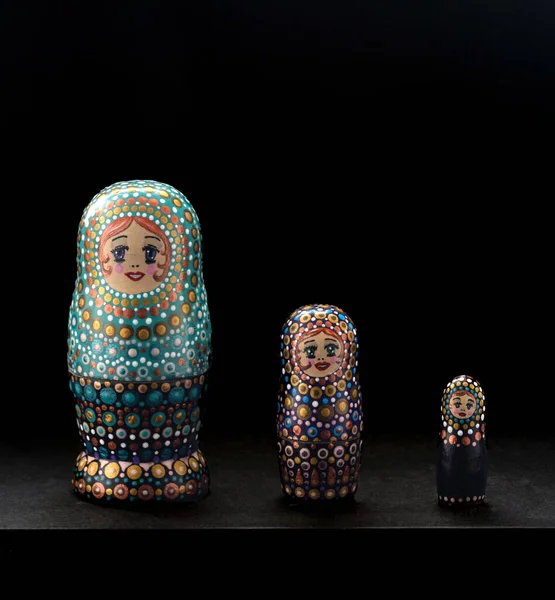 Wooden nesting dolls hand-painted. Traditional Russian toys nesting dolls. National coloring of figures. Isolated nesting dolls toy puzzle on black background.