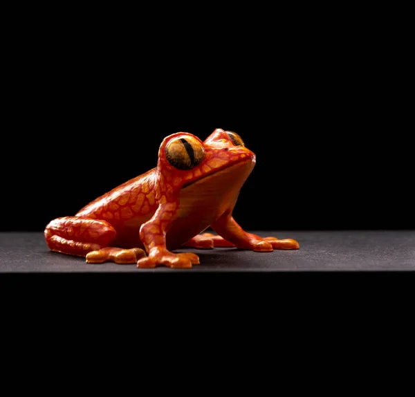 Isolated orange frog printed on a 3D printer on a black background close-up. The concept technology for 3d printing.