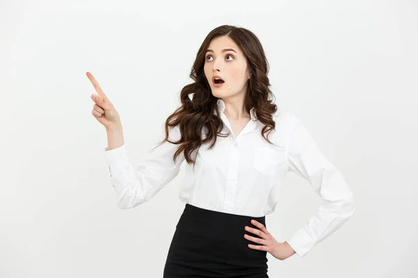 Business Concept: Portrait of surprised young businesswoman pointing finger away to copy space. Isolated on a white background. — Stock Photo, Image