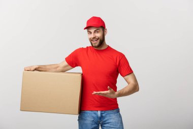 Teslimat kavramı - mutlu beyaz teslimat adam el işaret kutusunu paket sunuyoruz portresi. Arka plan gri studio izole. Kopya alanı.