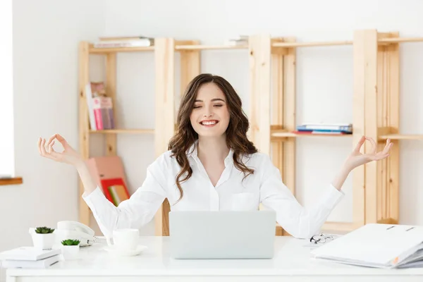 Business and Health Concept: Portrait young woman near the laptop, practicing meditation at the office desk, in front of laptop, online yoga classes, taking a break time for a minute.