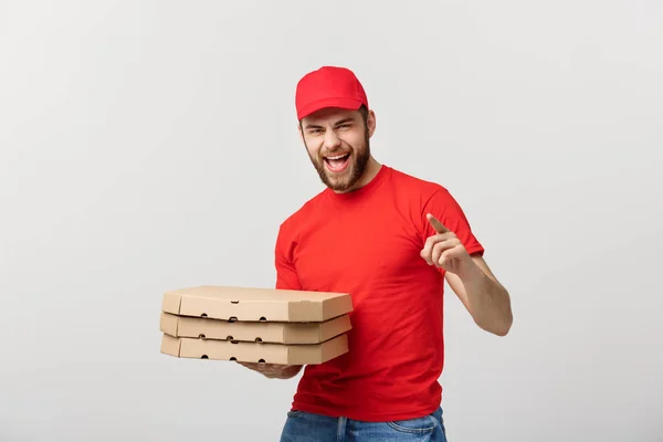 Lieferkonzept: Schöner Pizzabote in roter Uniform mit Mütze, auf der Pizzakartons stehen. Isoliert auf Weiß. — Stockfoto