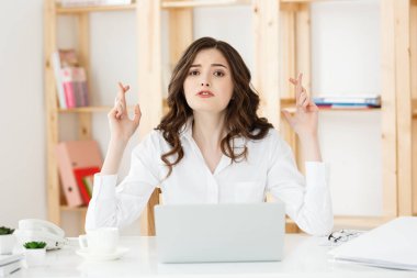 Ofis Masası oturma ve parmak tutan mutlu genç beyaz iş kadın portresi izole beyaz arka plan üzerinde çarpı işareti