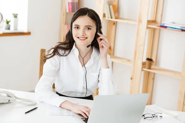 Young friendly operator woman agent or business woman with headsets working in a call centre.