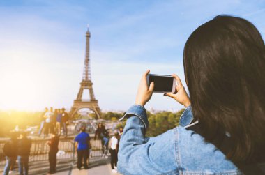 Kadın turist alarak fotoğraf güneş ve mavi gökyüzü altında Paris Eiffel tower yakınındaki telefonla. Dünyanın ünlü popüler bir turistik yer.