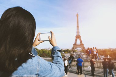 Kadın turist alarak fotoğraf güneş ve mavi gökyüzü altında Paris Eiffel tower yakınındaki telefonla. Dünyanın ünlü popüler bir turistik yer.