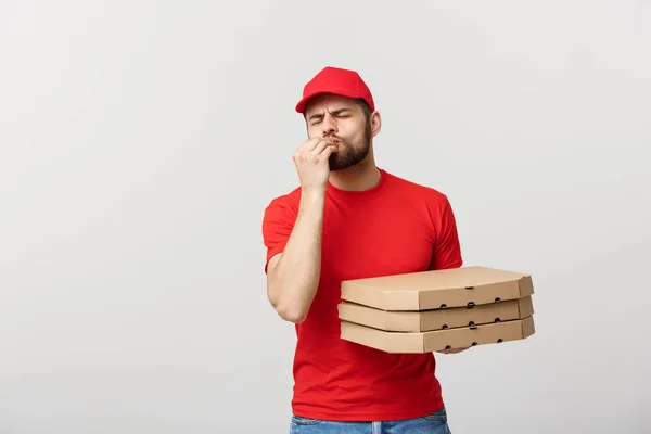 Lieferkonzept: Schöner Pizzabote mit leckerem Gesichtsausdruck vor grauem Hintergrund — Stockfoto