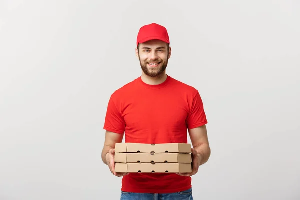 Χαρούμενος νεαρός deliveryman κρατώντας κουτιά πίτσας ενώ απομονώνονται σε φόντο λευκό στούντιο — Φωτογραφία Αρχείου