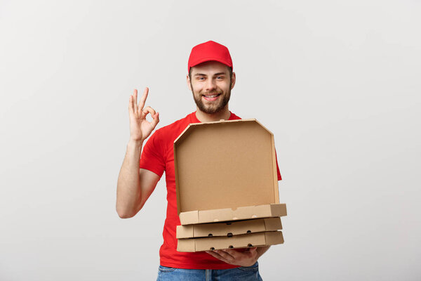 Delivery Concept: Handsome pizza delivery man making OK sign isolated over grey background.