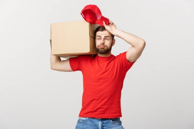 Teslimat konsepti: Kutuları, teslimatı ve endişeli yüz ifadesi olan kuryesi olan yakışıklı teslimatçı. İzole edilmiş gri arkaplan.