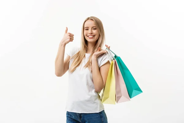 S úsměvem atraktivní žena držící nákupní tašky dělá palec podepsat na bílém pozadí s copyspace — Stock fotografie