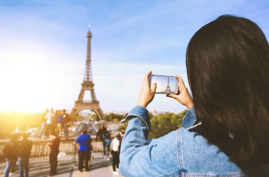 Kadın turist alarak fotoğraf güneş ve mavi gökyüzü altında Paris Eiffel tower yakınındaki telefonla. Dünyanın ünlü popüler bir turistik yer.