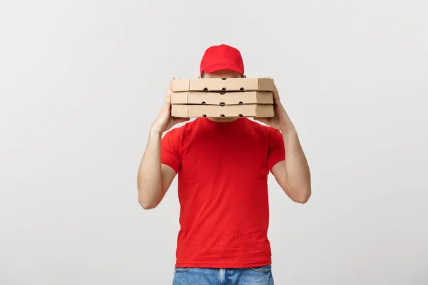 A Deliveryman hidden behind a large stack of pizza boxes he is carrying. Isolated over grey background.