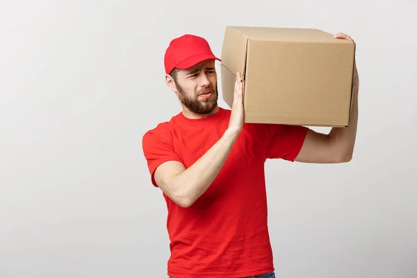 送货理念:英俊的送货人,有盒子,送货,快递员,脸上有忧虑的表情.孤立的灰色背景. — 图库照片