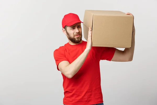 Lieferkonzept: gutaussehender Zusteller mit Kartons, Zustellung, Kurier mit sorgenvoller Miene. Vereinzelter grauer Hintergrund. — Stockfoto