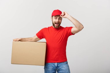 Teslimat Konsepti: genç beyaz yakışıklı teslimatçı omuzunda bir kutu tutuyor. Gri arkaplan üzerinde izole.