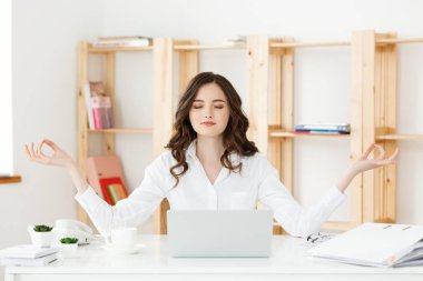 İş ve sağlık kavramı: meditasyon, ofis masası, dizüstü bilgisayar, online yoga dersleri, önünde bir dakikalığına mola zaman ayırdığınız pratik portre genç kadının yanına, dizüstü bilgisayar.