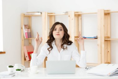 Ofis Masası oturma ve parmak tutan mutlu genç beyaz iş kadın portresi izole beyaz arka plan üzerinde çarpı işareti