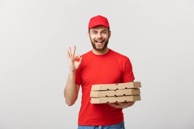 Teslim kavramı: yakışıklı pizza teslimat adam Ok işareti gri arka plan üzerinde izole yapma.