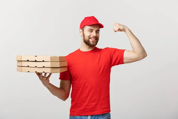 Concetto di consegna Ritratto di un uomo di consegna bello forte che flette i muscoli e tiene in mano pacchetti di scatole di pizza. Isolato su sfondo grigio studio. Copia spazio. — Foto Stock