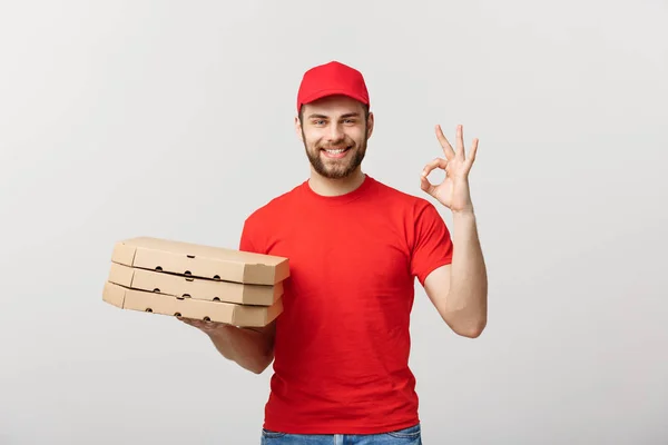 Lieferkonzept: Schöner Pizzabote macht Ok-Schild vor grauem Hintergrund. — Stockfoto