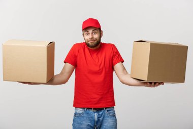 Teslimat tutan iki boş karton kutular beyaz arka plan üzerinde izole kırmızı üniformalı genç adam. Kopya alanı reklam için