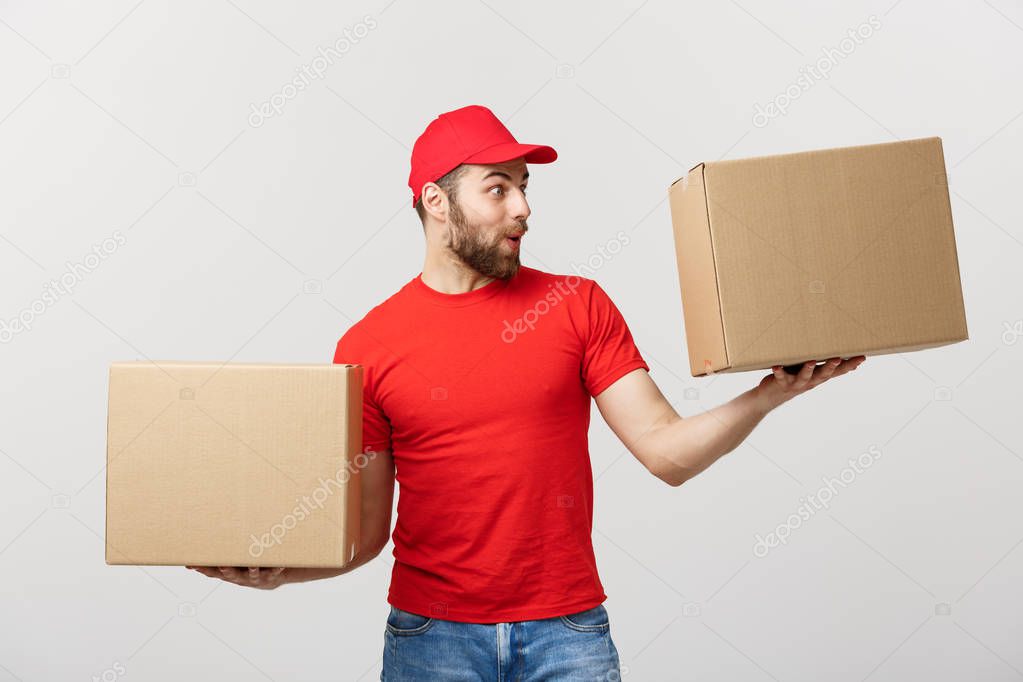 Delivery young man in red uniform holding two empty cardboard boxes isolated on white background. Copy space for advertisement