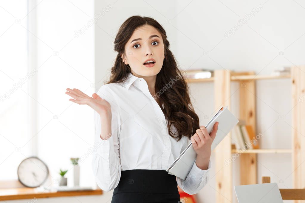 Shocked young business woman surprised by reading unexpected news in document, amazed woman office worker feeling stunned baffled by unbelievable information in paper about debt or dismissal