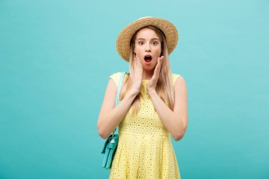 Şok ya da İyi Haber Konsepti: Uzun saçlı, uzun saçlı sarışın kız izole edilmiş mavi arka planda duruyor. Şaşkınlıkla ağzını açtı..