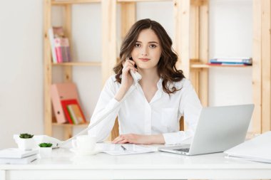 İş kavramı - genç güzel iş kadını ofiste telefonda konuşuyor