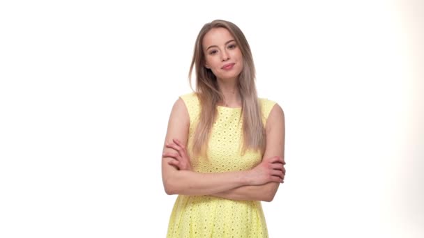 Lächelnde geheimnisvolle Frau im Kleid mit verschränkten Armen und Blick in die Kamera vor weißem Hintergrund — Stockvideo