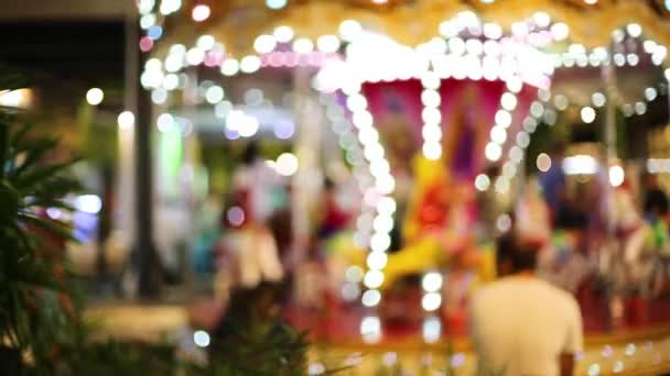 Blur kid playing on Carousel and bokeh of light at night. — Stock Video