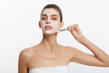Portre güzel çıplak kadın kozmetik beyaz kil maskesi fırça ile uygulanır. Beyaz bir arka plan üzerinde izole. Güzellik ve sağlık kavramı