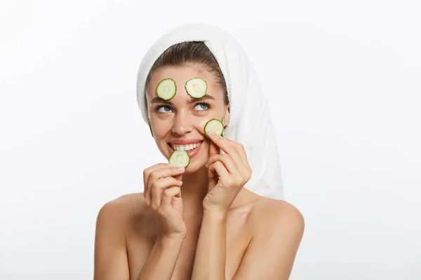 Femme avec masque facial et tranches de concombre dans ses mains sur fond blanc — Photo