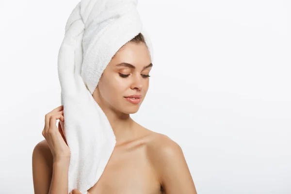 Спа и красота концепция - счастливая молодая девушка с чистой кожей и с белым полотенцем на голове умывает лицо — стоковое фото