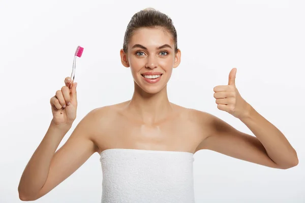 Young woman brushing cleaning teeth. Girl holds toothbrush with toothpaste on it showing thumb up hand gesture. Oral hygiene. — Stock Photo, Image