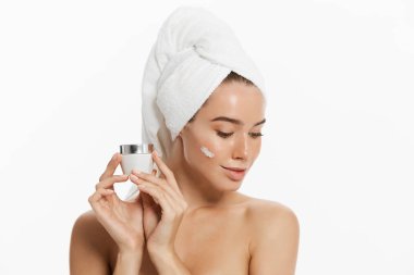 Beyaz arka plan üzerinde izole yüz kremini uygulamadan bir gülümseyen güzel yarı çıplak kadın güzellik portresi kapatın.