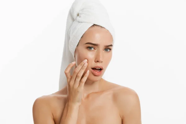 Giovane donna infelice che trova un'acne su una guancia. Isolato su sfondo bianco — Foto Stock