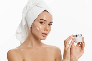 Beyaz arka plan üzerinde izole yüz kremini uygulamadan bir gülümseyen güzel yarı çıplak kadın güzellik portresi kapatın.