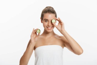 Genç güzel, mutlu kadın bazı salatalık gülümseyen yüzünü önünde tutuyor. Beyaz arka plan üzerinde izole.