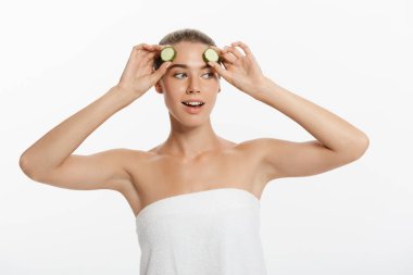 Beyaz arka plan üzerinde izole salatalık dilimleri tutan genç kadın