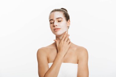 Yüzünün yarısına krem sürmüş, beyaz tenli bir kadın.