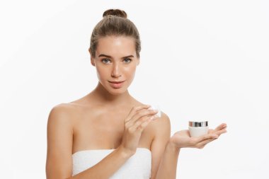 Yüzünde beyaz arka plan üzerinde izole kozmetik krem tedavisi uygulayarak güzel genç kadın