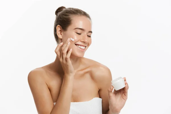 Mulher bonita aplicando tratamento de creme cosmético em seu rosto isolado no fundo branco — Fotografia de Stock