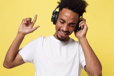 Çekici bir Afrikalı-Amerikalı adam kulaklık ile müzik dinlemek. Sarı altın arka plan üzerinde izole.